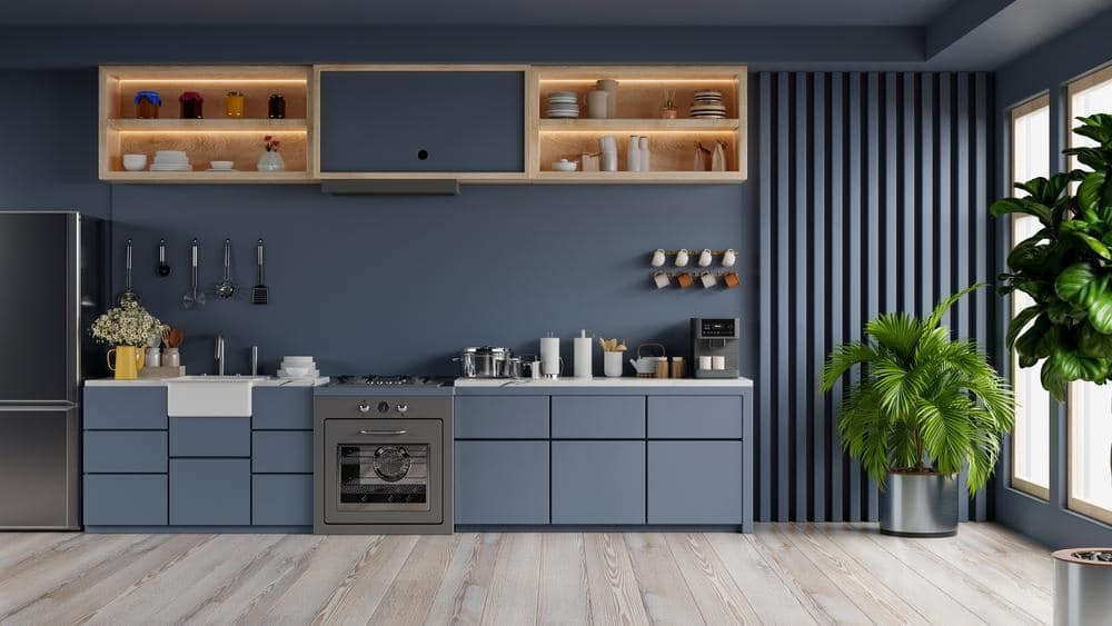 wooden floor kitchen with dark blue handleless cabinets and drawers and a plant next to cabinets