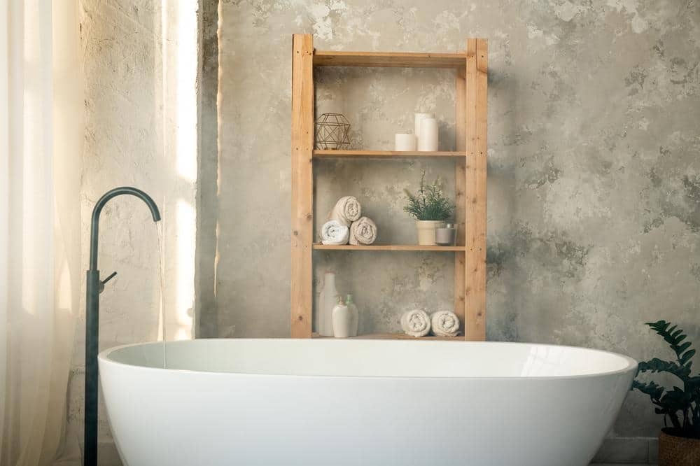 large bathtub next to wooden shelves in a bathroom
