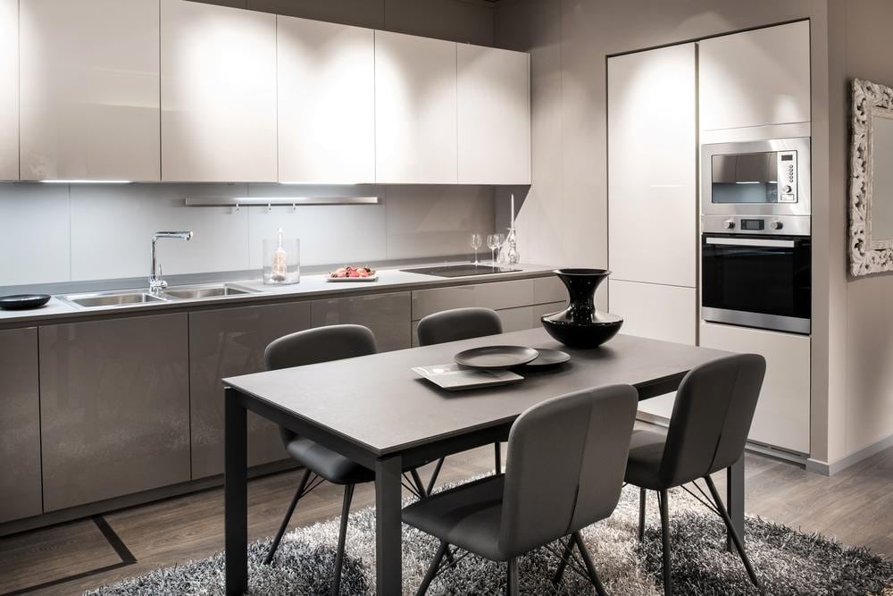 grey kitchen with handleless cabinets and dining table with four chairs in the middle of the room