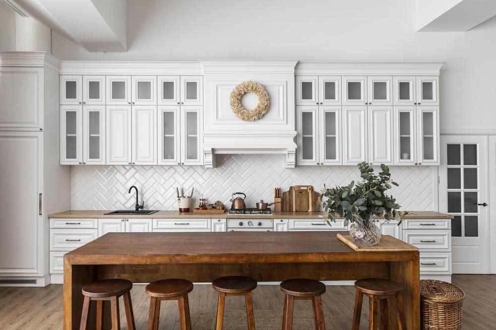 classic style white kitchen cabinets in a kitchen with dark wooden dining table with stools
