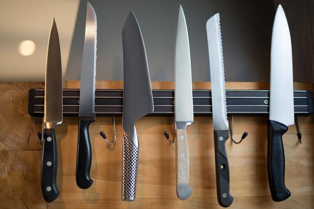 set of kitchen knives hanging on the wooden wall