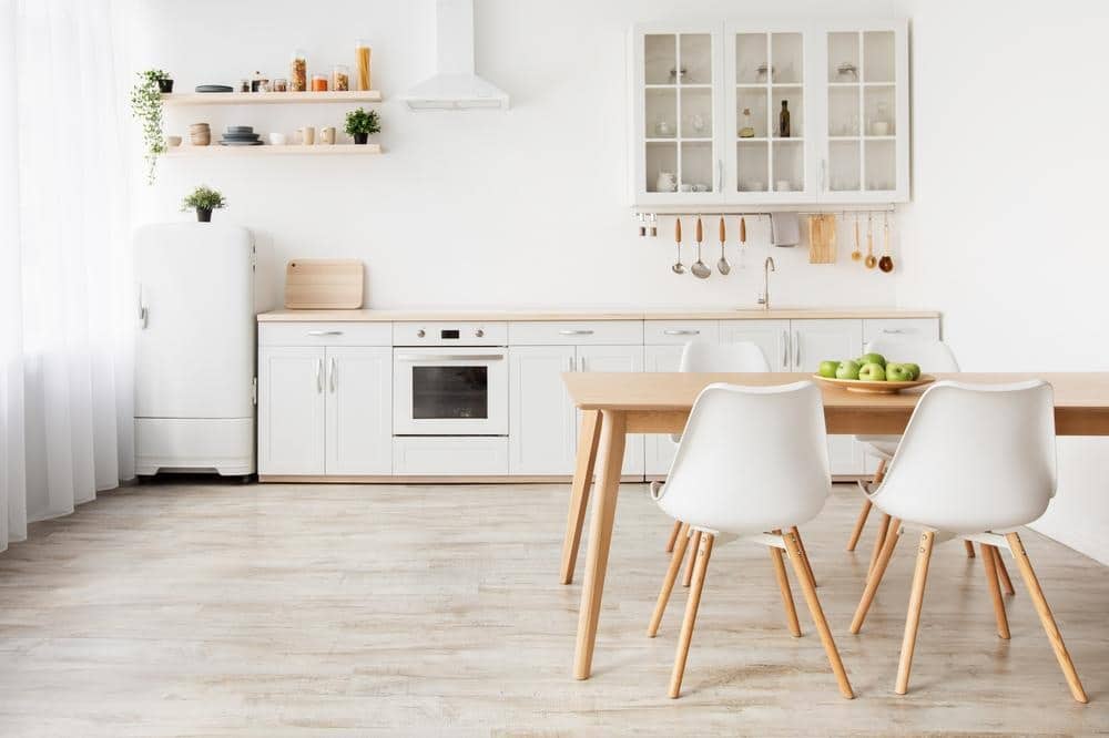 white and light wooden kitchen furniture inside of a kitchen with wooden floor