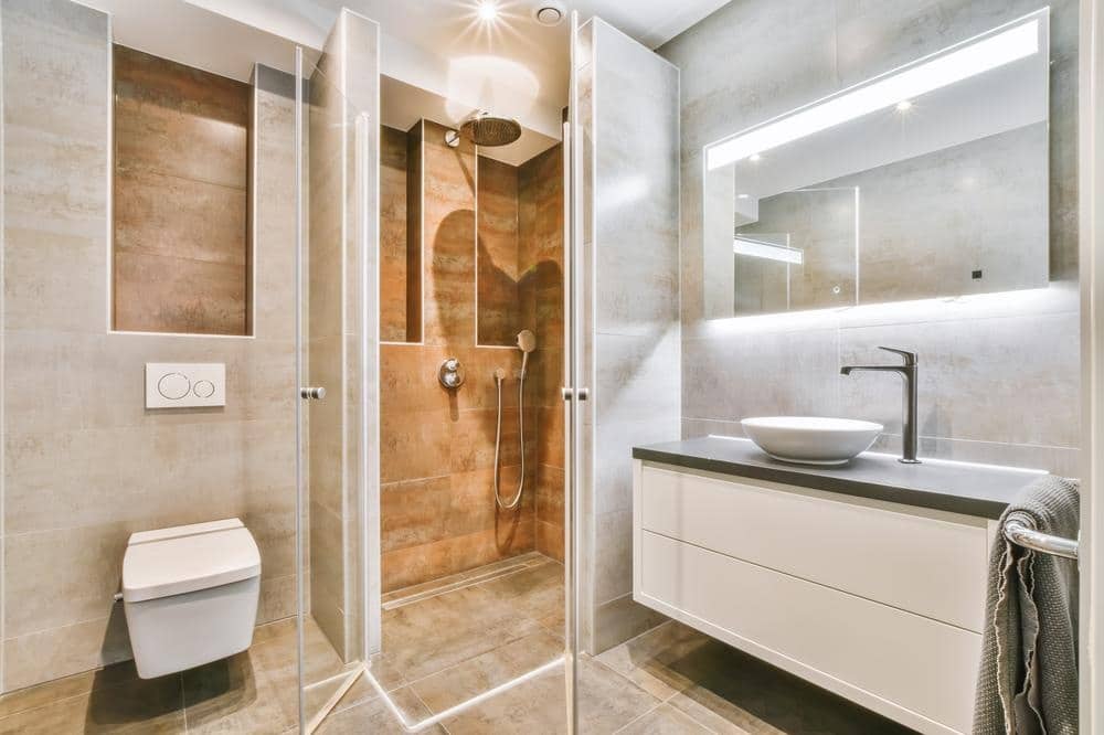 small bathroom with marble floor and lighted mirror