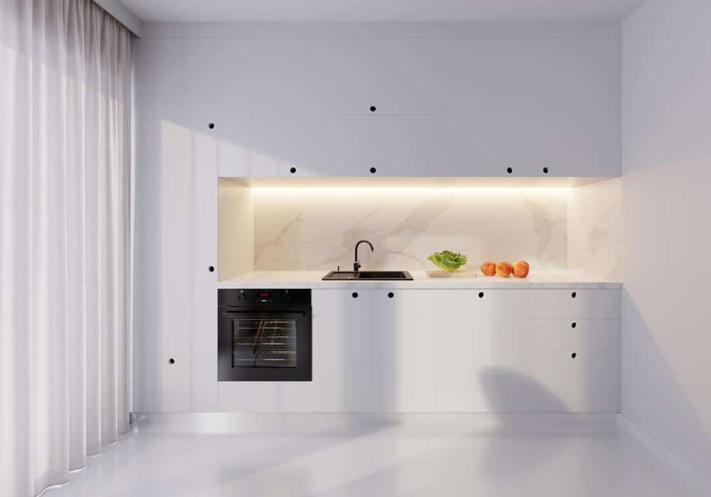 white kitchen with white cabinets and black handles with lighted countertop