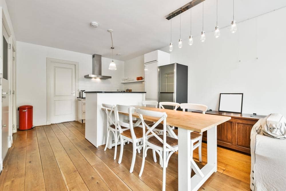 kitchen with wooden flooring and white chairs next to dining table